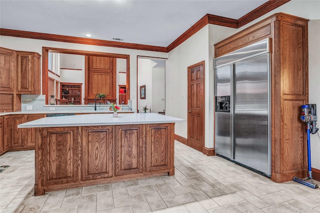 11086 Tenison Ln, Frisco, TX 75033 - kitchen featuring stainless steel built in fridge, brown cabinets, crown molding, light countertops, and a kitchen island