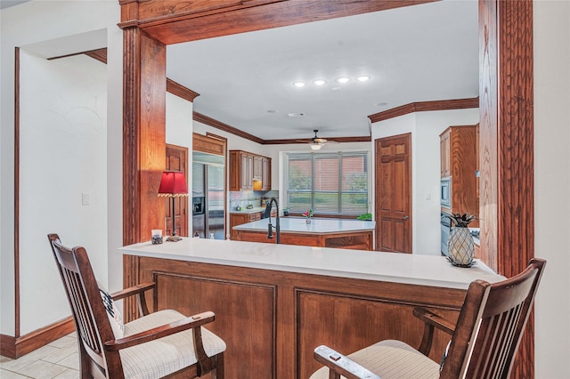11086 Tenison Ln, Frisco, TX 75033 - kitchen with built in appliances, a peninsula, crown molding, a ceiling fan, and brown cabinets