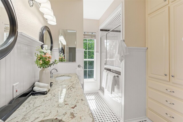 561 Farms Rd, New Hope, TX 75071 - bathroom with wainscoting, a stall shower, a decorative wall, double vanity, and tile patterned floors