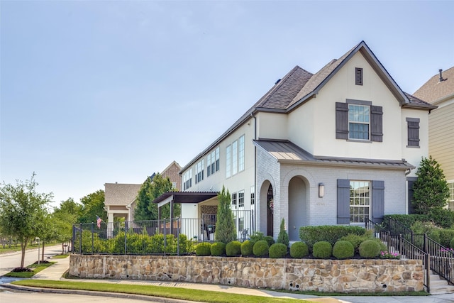4944 Sage Hill Dr, Carrollton, TX 75010 - view of front facade featuring brick siding, a standing seam roof, fence, metal roof, and stucco siding