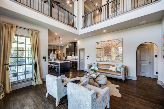 4944 Sage Hill Dr, Carrollton, TX 75010 - living area with arched walkways, dark wood-style flooring, a towering ceiling, and baseboards