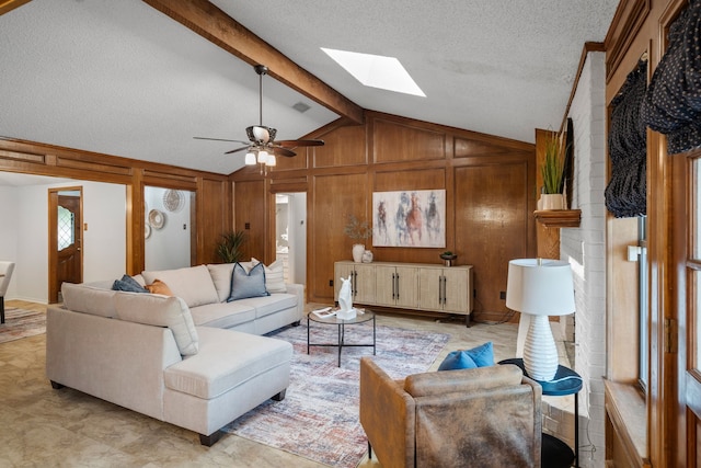 1009 Windmill Ln, Irving, TX 75061 - living room with a skylight, ceiling fan, wood walls, a textured ceiling, and a fireplace