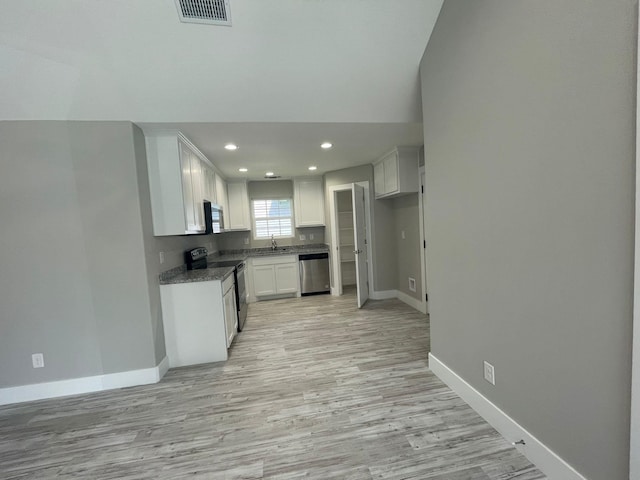 1315 W Gandy St, Denison, TX 75020 - kitchen featuring appliances with stainless steel finishes, baseboards, a sink, light wood finished floors, and white cabinetry