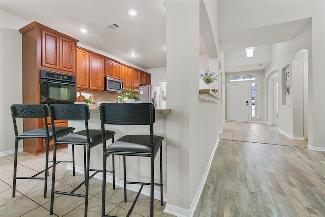 7804 Rampston Pl, Fort Worth, TX 76137 - kitchen featuring stainless steel appliances, a kitchen breakfast bar, baseboards, tasteful backsplash, and recessed lighting