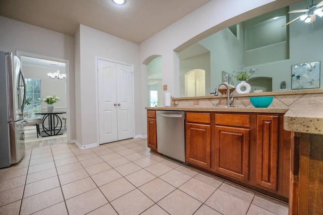 7804 Rampston Pl, Fort Worth, TX 76137 - kitchen featuring stainless steel appliances, a sink, brown cabinetry, light tile patterned floors, and light countertops