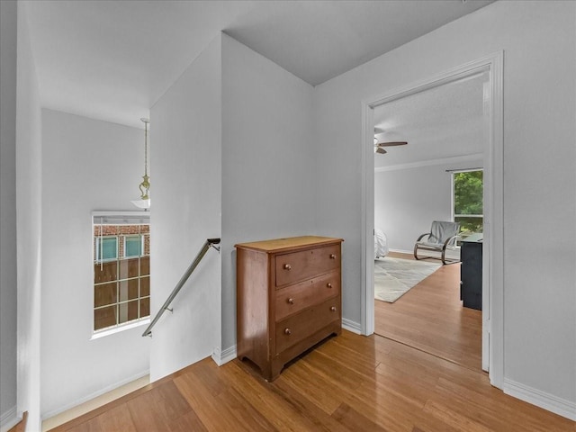 hallway featuring an upstairs landing, wood finished floors, and baseboards