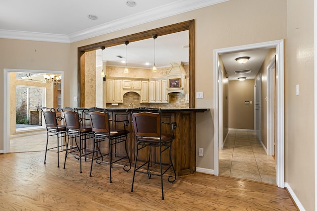 3740 Chimney Ridge Dr, Waco, TX 76708 - kitchen featuring dark countertops, a kitchen bar, light wood-style flooring, decorative backsplash, and crown molding