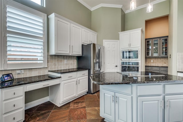 kitchen featuring stainless steel appliances, ornamental molding, white cabinetry, tasteful backsplash, and dark stone counters
