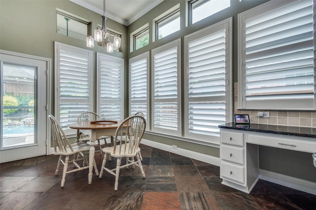 dining space with crown molding, a chandelier, a desk, and dark stone finish flooring