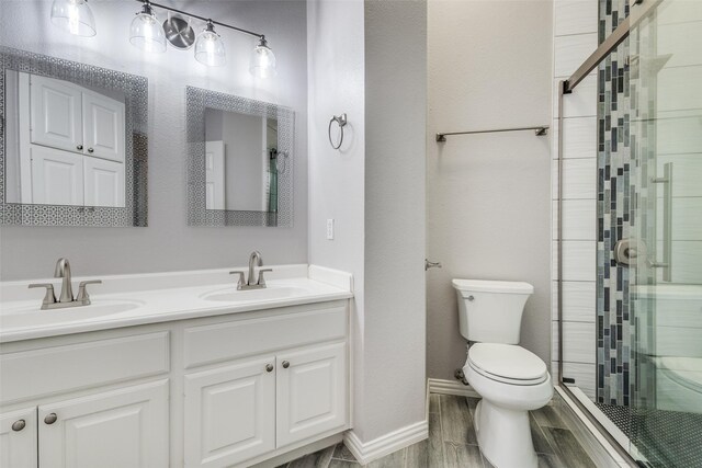 full bath featuring toilet, a stall shower, double vanity, and wood finished floors