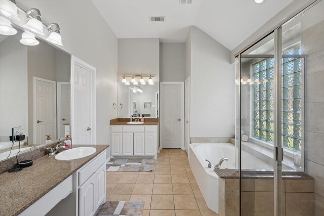 1601 Manchester Way, Corinth, TX 76210 - bathroom featuring plenty of natural light, vaulted ceiling, two vanities, a garden tub, and tile patterned flooring
