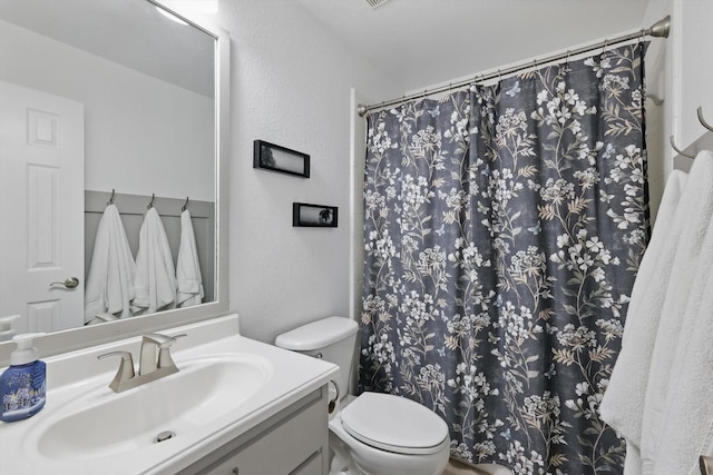 1601 Manchester Way, Corinth, TX 76210 - bathroom featuring a textured wall, toilet, vanity, and curtained shower