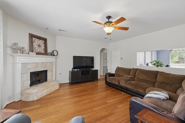 1601 Manchester Way, Corinth, TX 76210 - living area featuring light wood finished floors, ceiling fan, a stone fireplace, and arched walkways