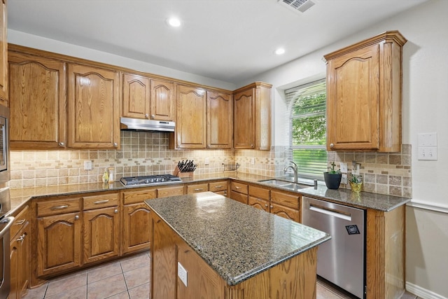 1601 Manchester Way, Corinth, TX 76210 - kitchen featuring appliances with stainless steel finishes, a sink, under cabinet range hood, dark stone countertops, and brown cabinetry