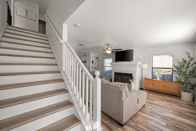 6612 Oldgate Ln, Arlington, TX 76002 - living room with a fireplace, stairway, a ceiling fan, and light wood-type flooring