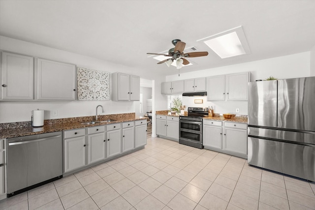 6612 Oldgate Ln, Arlington, TX 76002 - kitchen featuring stainless steel appliances, a sink, a ceiling fan, dark stone countertops, and under cabinet range hood