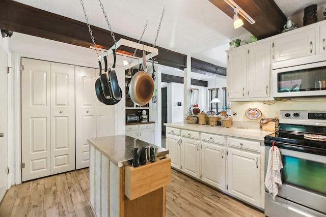 203 Goodson Way, Denton, TX 76207 - kitchen featuring white microwave, electric stove, light wood-style floors, white cabinetry, and beam ceiling