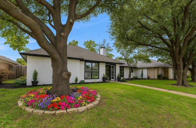 mid-century inspired home featuring a chimney and brick siding