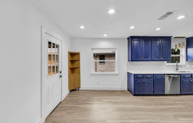 kitchen featuring dishwasher, a sink, blue cabinetry, light wood-style floors, and light countertops