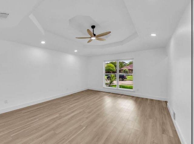 unfurnished room with a tray ceiling, ceiling fan, light wood-style flooring, baseboards, and recessed lighting