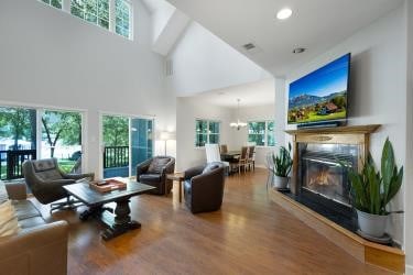 7095 Lance Ln, Eustace, TX 75124 - living area featuring high vaulted ceiling, wood finished floors, a glass covered fireplace, a chandelier, and recessed lighting