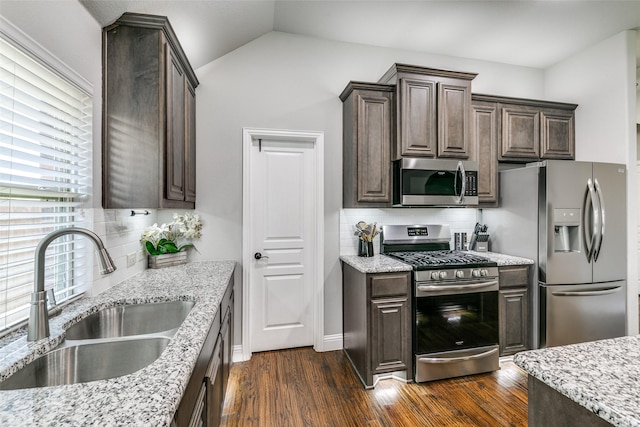 936 Mangrove Dr, Fate, TX 75087 - kitchen with stainless steel appliances, a sink, dark brown cabinets, tasteful backsplash, and lofted ceiling