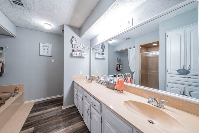 916 Rachelle Dr, Red Oak, TX 75154 - bathroom featuring wood finished floors, a stall shower, double vanity, a garden tub, and a textured ceiling