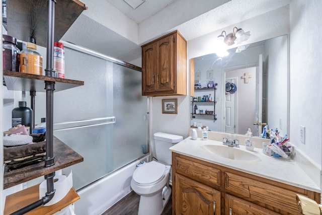 916 Rachelle Dr, Red Oak, TX 75154 - bathroom featuring toilet, wood finished floors, bath / shower combo with glass door, vanity, and a textured ceiling