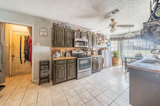 916 Rachelle Dr, Red Oak, TX 75154 - kitchen with stainless steel appliances, ceiling fan, light tile patterned flooring, a sink, and dark brown cabinetry
