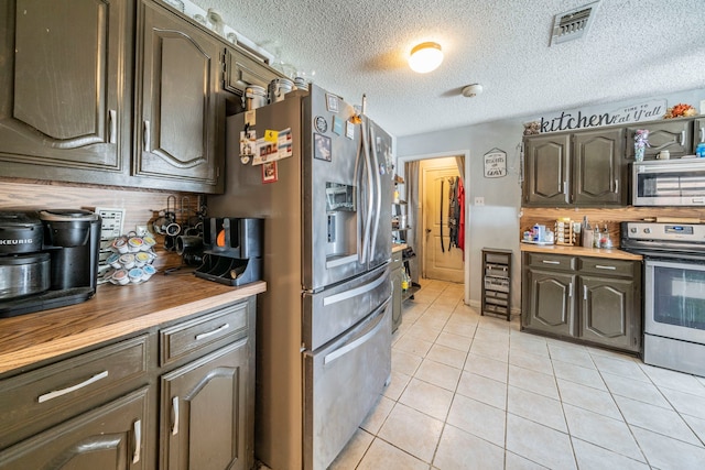916 Rachelle Dr, Red Oak, TX 75154 - kitchen with stainless steel appliances, tasteful backsplash, light tile patterned floors, butcher block counters, and a textured ceiling