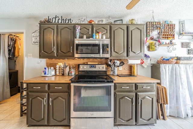 916 Rachelle Dr, Red Oak, TX 75154 - kitchen with appliances with stainless steel finishes, a textured ceiling, light tile patterned flooring, butcher block countertops, and decorative backsplash