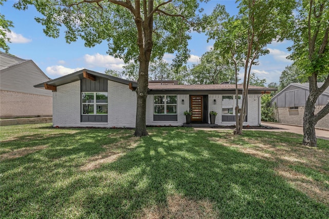 view of front of house featuring brick siding, a front lawn, and board and batten siding