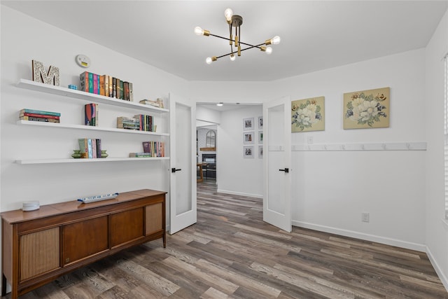 hall with a chandelier, wood finished floors, and baseboards