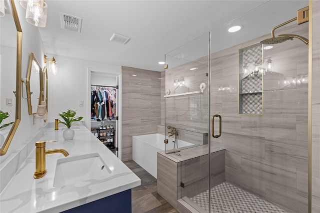 bathroom with a stall shower, a freestanding tub, recessed lighting, and double vanity