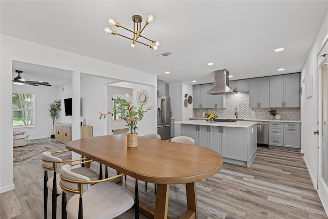 dining space with light wood-style floors, a ceiling fan, a chandelier, and recessed lighting
