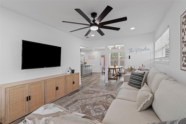 living room featuring a chandelier, light wood-style floors, a ceiling fan, and recessed lighting