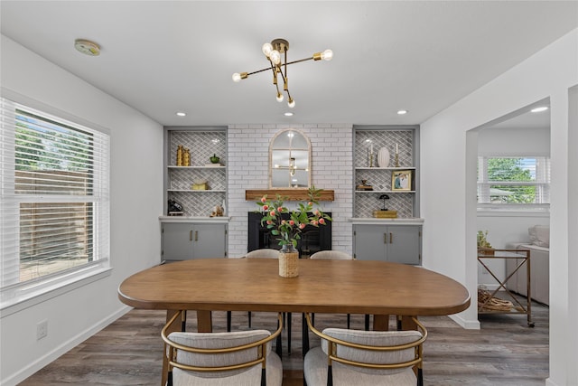 dining room featuring a chandelier, wood finished floors, baseboards, a brick fireplace, and recessed lighting