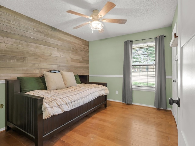 616 Stoneybrook Dr, Wylie, TX 75098 - bedroom with wooden walls, a textured ceiling, baseboards, wood finished floors, and ceiling fan