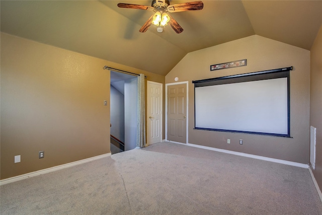 carpeted cinema room featuring ceiling fan, vaulted ceiling, and baseboards