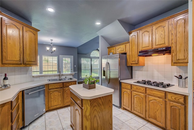 kitchen with appliances with stainless steel finishes, under cabinet range hood, a sink, a center island, and brown cabinets