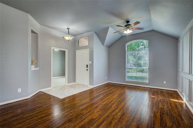 unfurnished living room with hardwood / wood-style floors, ceiling fan, lofted ceiling, and baseboards