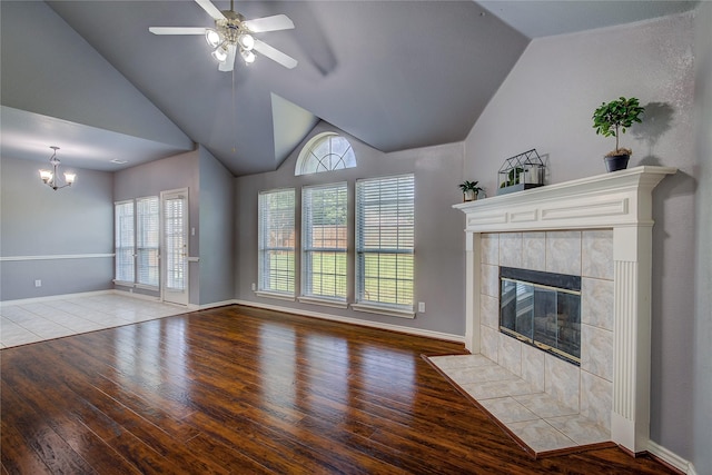 unfurnished living room featuring lofted ceiling, wood finished floors, healthy amount of natural light, and a tiled fireplace