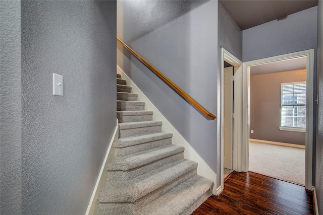 stairs featuring wood finished floors, a textured wall, and baseboards