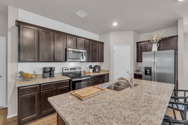 3005 Sherco Rd, Waco, TX 76655 - kitchen featuring appliances with stainless steel finishes, a sink, dark brown cabinetry, a kitchen bar, and a center island with sink