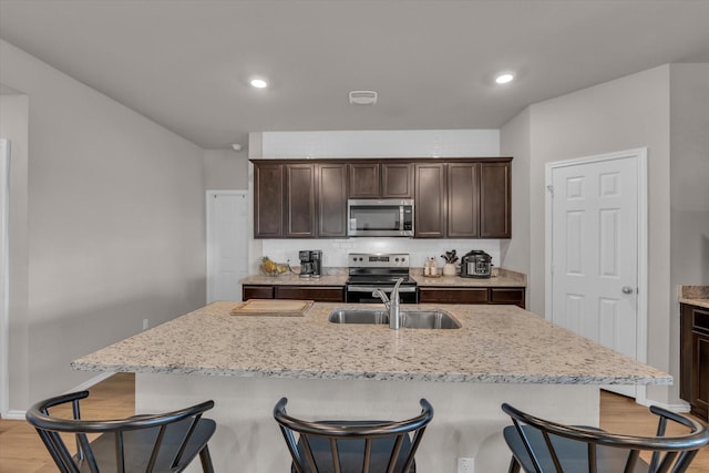 3005 Sherco Rd, Waco, TX 76655 - kitchen with appliances with stainless steel finishes, a sink, a breakfast bar area, light wood finished floors, and recessed lighting