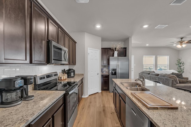 3005 Sherco Rd, Waco, TX 76655 - kitchen with stainless steel appliances, a sink, light wood-type flooring, dark brown cabinets, and recessed lighting