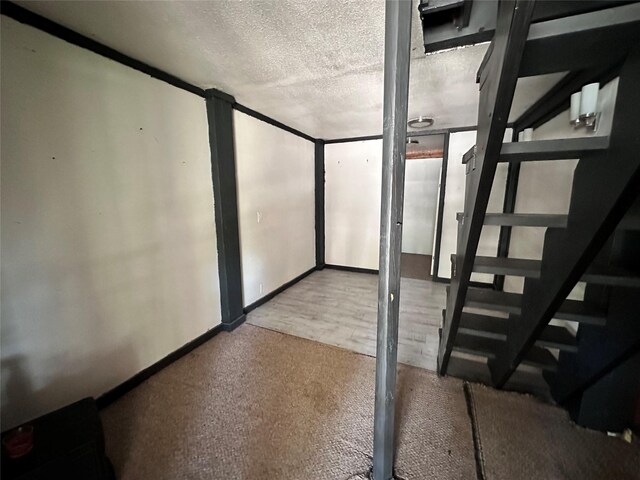 4320 Comanche Dr, May, TX 76857 - below grade area featuring a textured ceiling, carpet floors, stairs, and baseboards