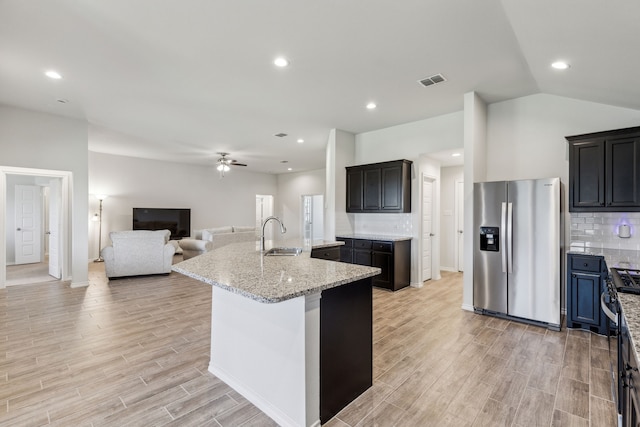 3006 Genevieve Ln, Royse City, TX 75189 - kitchen with stainless steel appliances, a sink, open floor plan, a center island with sink, and light wood finished floors