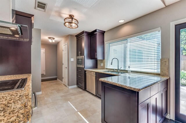 3604 Windsong Ln, Bedford, TX 76021 - kitchen featuring a sink, stainless steel appliances, baseboards, light stone countertops, and a peninsula