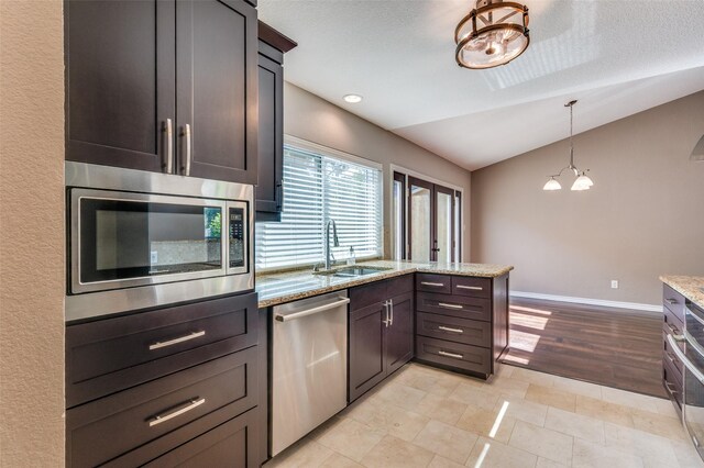 3604 Windsong Ln, Bedford, TX 76021 - kitchen featuring stainless steel appliances, a sink, lofted ceiling, a peninsula, and light stone counters